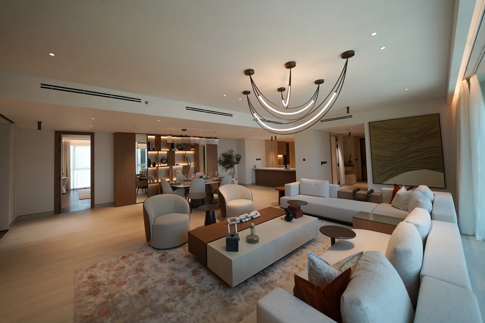 The living room: sofas and tub chairs around the coffee table, the branched chandelier, the painting, the dining area and the hallway