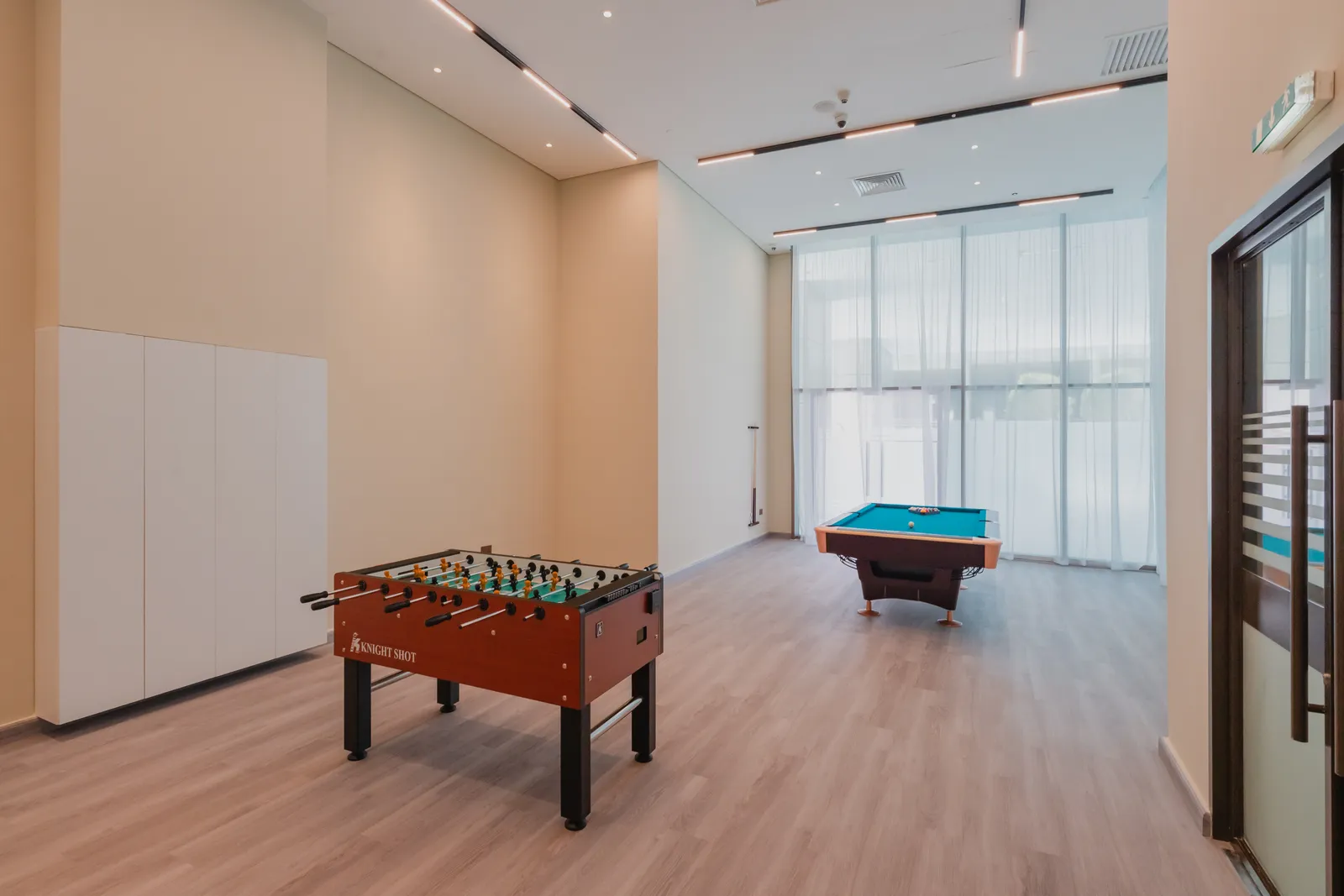 The games room: table football and the billiards table, white cupboards and a glazed door