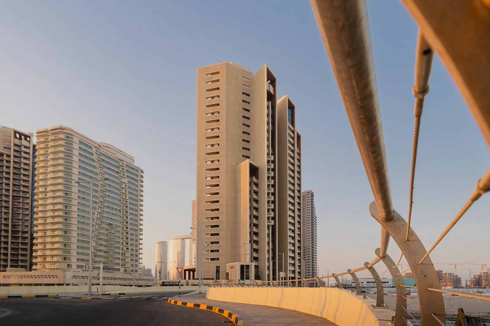 Baheen Tower seen from the bridge approach road, with the bridge cables in the foreground and neighbouring towers to the left