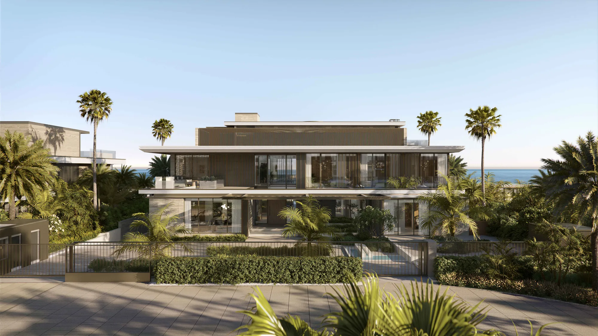 A seven-bedroom villa from its garden: a wide two-storey house among palms, the sea behind